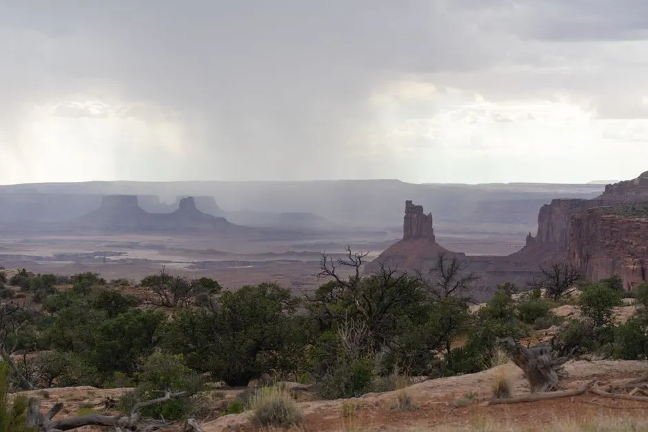 Breathtaking view of the rugged canyon landscape in Moab, Utah under overcast skies with rain showers.